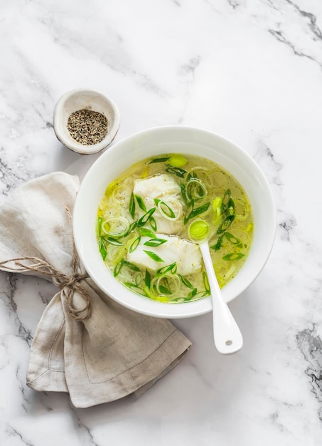 Kabeljau-Lauch- und Reisbrühe auf hellem Marmorhintergrund Draufsicht Köstliche Diätsuppe zum Mittagessen