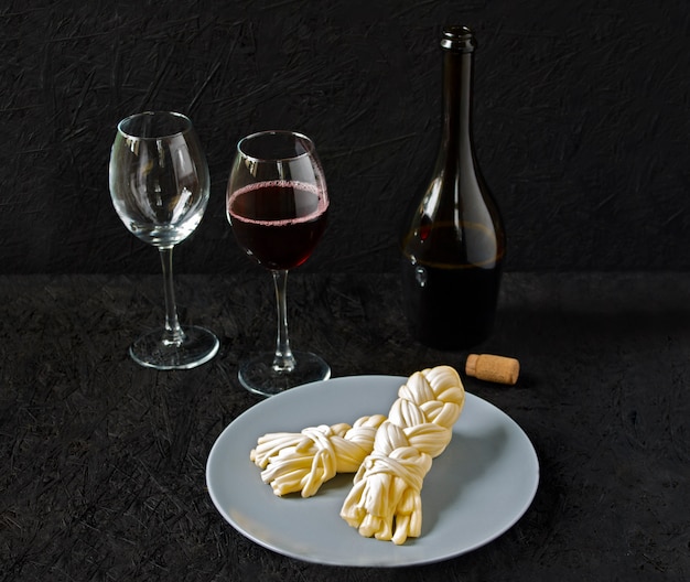 Käse auf einer Platte und Wein auf einem schwarzen Hintergrund. Sulguni-Käse