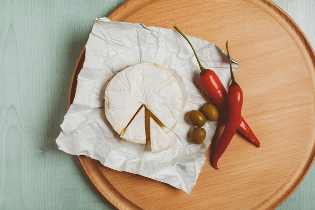 Käse Brie Camembert grüne Oliven Chili auf einem hölzernen hellen Hintergrund Vintage Fotoverarbeitung