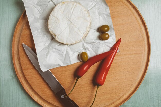 Käse Brie Camembert grüne Oliven Chili auf einem hölzernen hellen Hintergrund Vintage Fotoverarbeitung