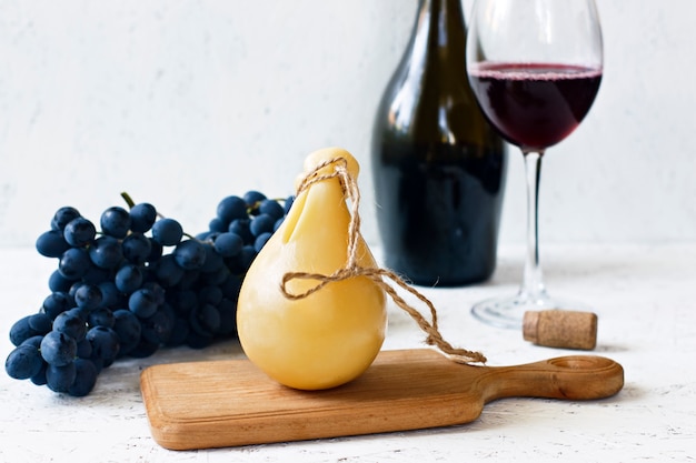 Käse Caciocavallo ein Glas und eine Flasche Rotwein, Trauben. Käse Birne