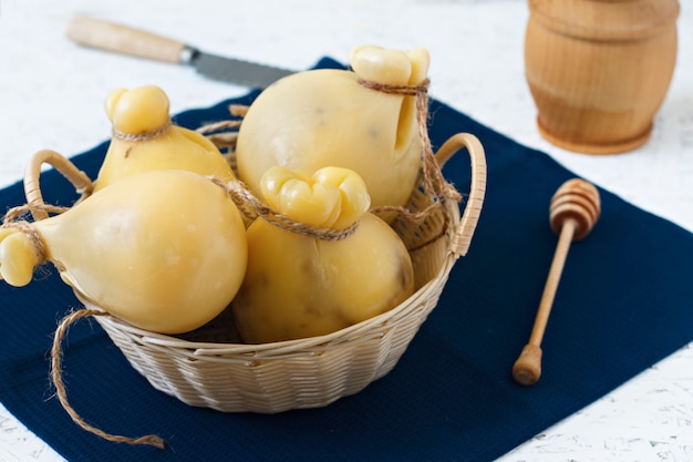 Käse Caciocavallo in einem Korb mit Honig auf einem weißen Hintergrund. Käse Birne