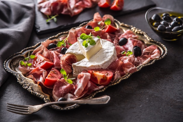 Foto käse camambert aus prosciutto oder coppa schinken tomaten oliven und oregano kräutern.