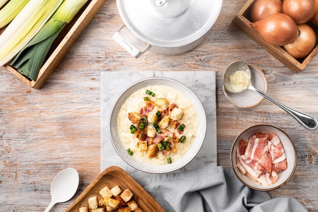 Käse-Lauch-Suppe mit Croutons und Speck in einer Schüssel auf einem Holztisch von oben