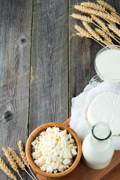 Käse, milch, hüttenkäse und weizen auf altem holz