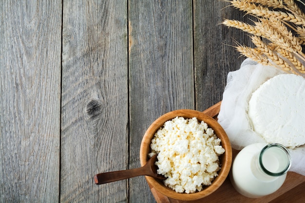 Käse, Milch, Hüttenkäse und Weizen auf altem Holz