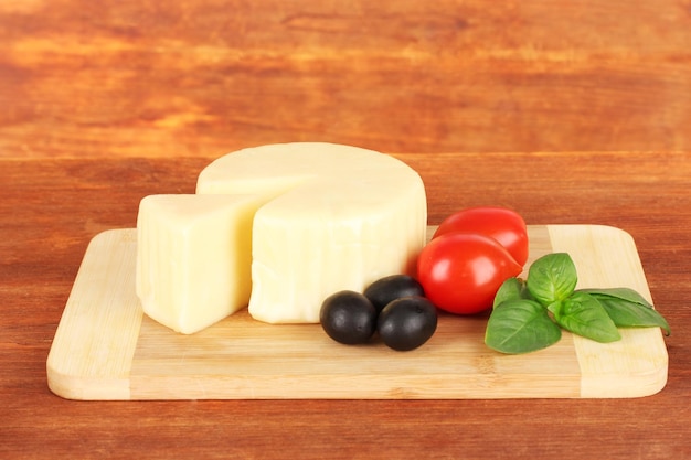 Käse, Mozzarella, Basil und Gemüse auf hölzern Hintergrund