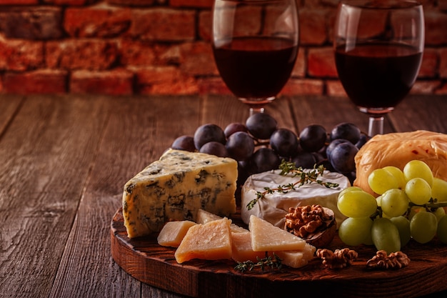 Käse, Nüsse, Trauben und Rotwein auf hölzernem Hintergrund