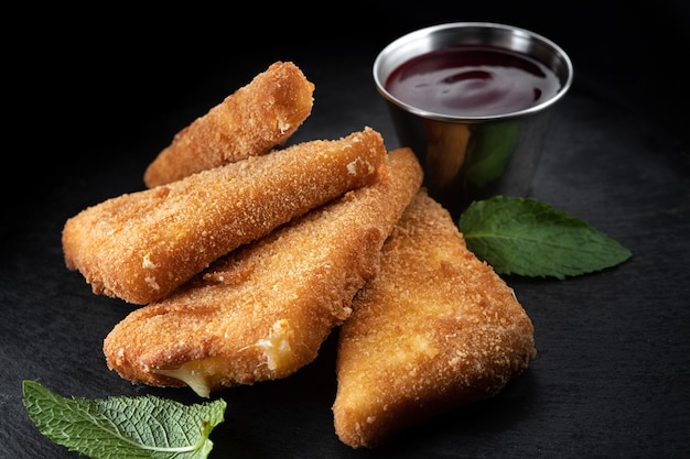 Käse-Nuggets mit Himbeersauce und Minze, auf einem schwarzen Hintergrund