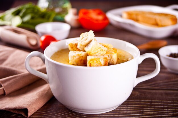 Käse- oder Zwiebelcremesuppe mit Toastbrot in einer weißen Schüssel