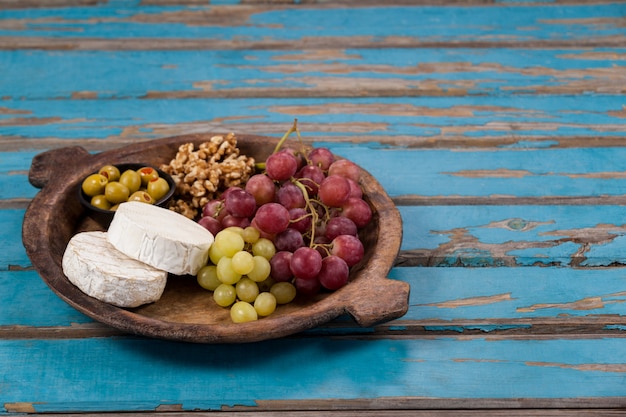 Käse, Trauben, Oliven und Walnüsse in Holzschale