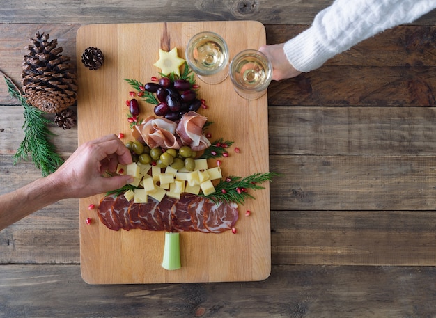 Käse- und Wurstbrett in Weihnachtsbaumform. Zwei Leute essen. Platz kopieren. Ansicht von oben.