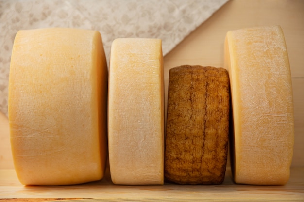 Käse verschiedener Sorten auf Naturholzuntergrund ganz und geschnitten
