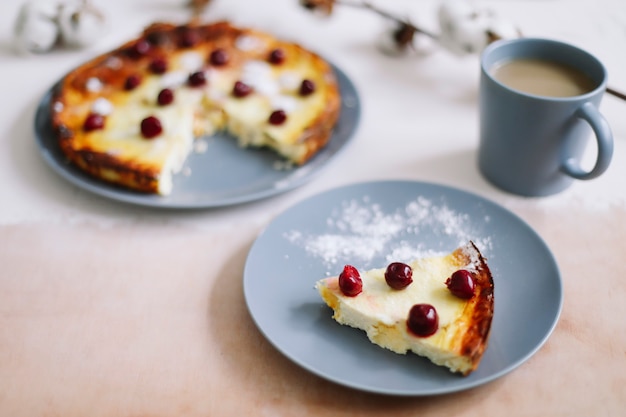 Käseauflauf mit Beeren und einer Tasse Kaffee auf Tischplatte-Ansicht