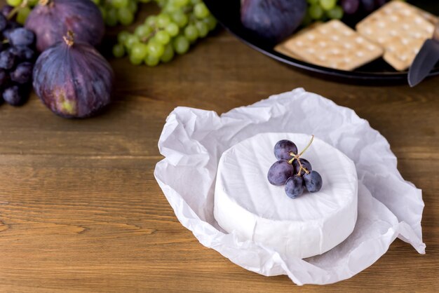 Käsebrie Camembert mit Feigen und Trauben auf Holztisch Essen für Weinfeigen Grüne und rote Trauben Cracker Messerplatte Snacks Kopierraum