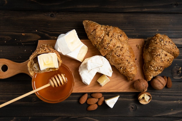 Käsebrie- oder Camembertscheiben mit Croissants, Honig und Nüssen an Bord zum Schneiden