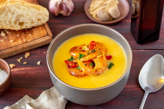 Käsecremesuppe mit gegrillter Garnele auf einem hölzernen Hintergrund.