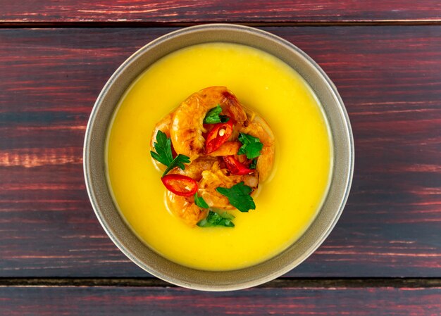 Käsecremesuppe mit gegrillter Garnele auf einem hölzernen Hintergrund.