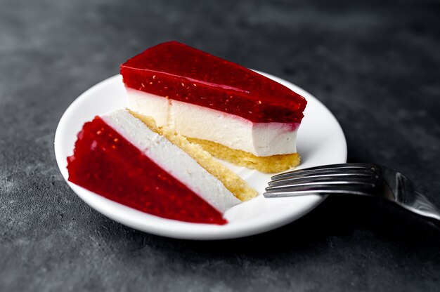 Käsekuchen-Kuchen mit Himbeeren auf einer weißen Untertasse auf einem Steinhintergrund