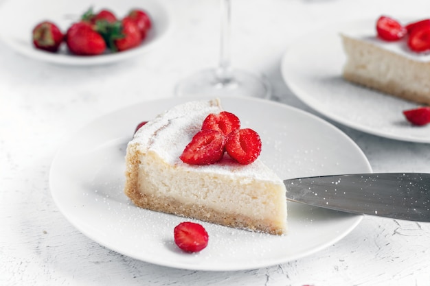 Käsekuchen mit Erdbeeren auf einem weißen Teller verziert