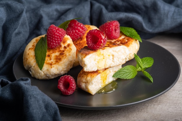 Foto käsekuchen mit minze, himbeeren, honig. frühstücksmahlzeit der ukrainischen, russischen küche. hausgemachtes essen.