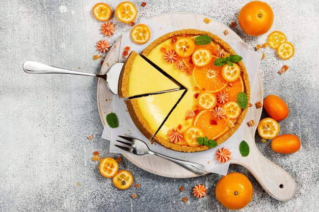 Käsekuchen mit Orangen- und Kumquatscheiben auf grauem Steinhintergrund Draufsicht