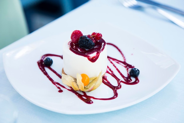 Käsekuchen mit roter Fruchtsauce und frischen Früchten wie Himbeeren, Heidelbeeren oder Erdbeeren.