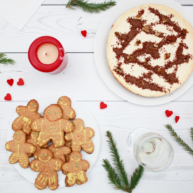 Käsekuchen mit Schokolade auf dem hölzernen Hintergrund Draufsicht Tannenzweige Weihnachten Lebkuchen Mann Plätzchen Lebkuchen des neuen Jahres