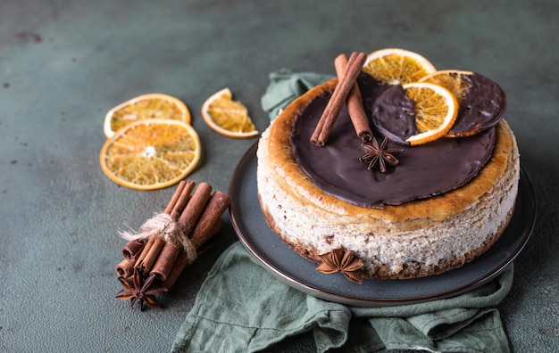 Käsekuchen mit schokoladenverzierten Scheiben getrockneter Orangen, Zimt und Anis