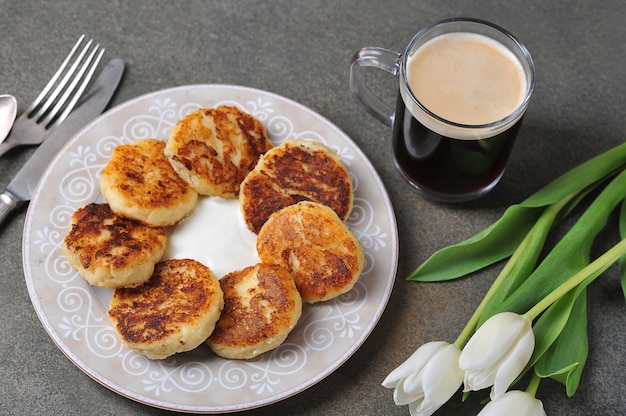 Käsekuchen und eine Tasse Kaffee und weiße Tulpen