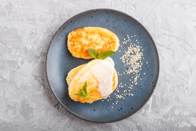 Käsepfannkuchen auf einer blauen keramischen Platte mit Milchsoße