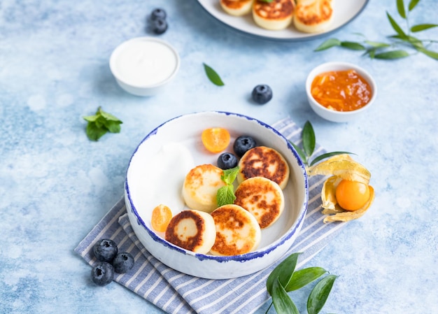 Käsepfannkuchen Krapfen oder Syrniki mit Heidelbeer-Physalis und Joghurt Gesundes und leckeres Frühstück