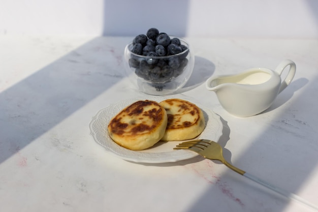 Käsepfannkuchen mit Heidelbeeren auf einem weißen Tisch Morgenstrahlen der Sonne Guten Morgen-Postkarte