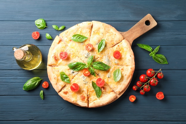 Käsepizza, Tomaten und Olivenöl auf hölzernem Hintergrund