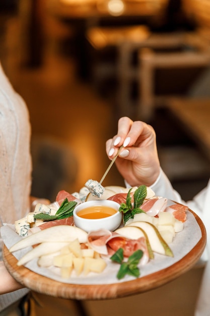 Käseplatte mit Honig in einem Restaurant Frauenhände tauchen Käse in Honig