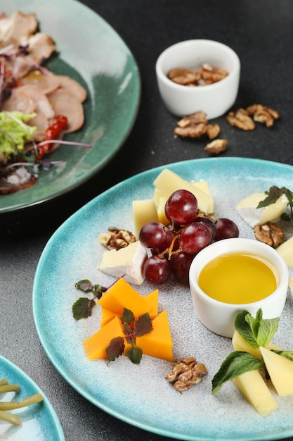 Käseplatte mit Honig und Traube auf dunklem Betontisch. Abendessen Konzept.