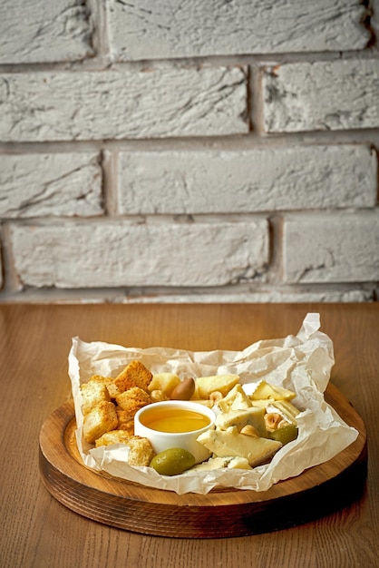Käseplatte mit Oliven Croutons Honig in einem Teller auf Holzhintergrund Verschiedene Käsesorten Antipasti-Käseplatte