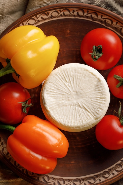 Käseplatte mit Tomaten und Paprika auf rustikal. Draufsicht