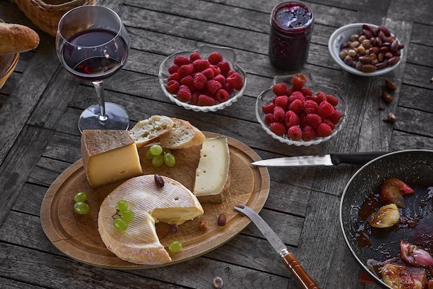 Käsesortiment auf einem Holztablett mit Wein, auf dem Tisch, Hausterrasse, tagsüber gibt es keine Menschen