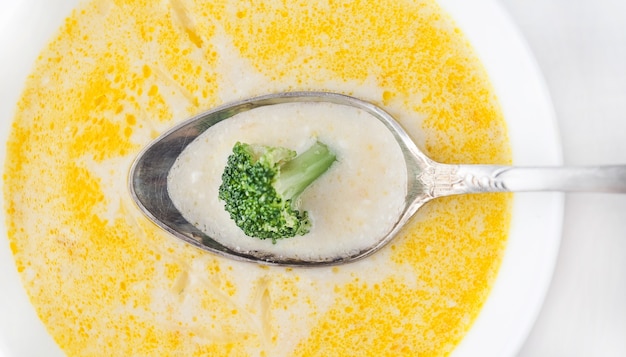 Käsesuppe mit Brokkoli in einem weißen Teller auf einer weißen Leinentischdecke