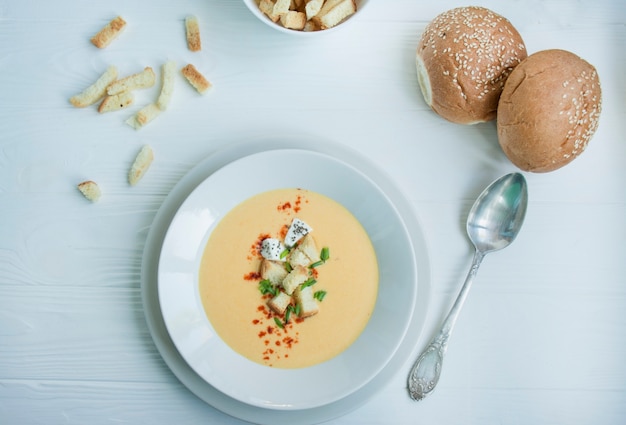 Käsesuppe mit Crackern, Kräutern und Feta. Cremesuppe in einem weißen Teller serviert. Weiß .