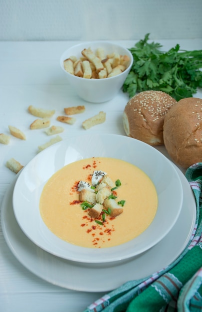 Käsesuppe mit Crackern, Kräutern und Feta. Cremesuppe in einem weißen Teller serviert. Weiß .