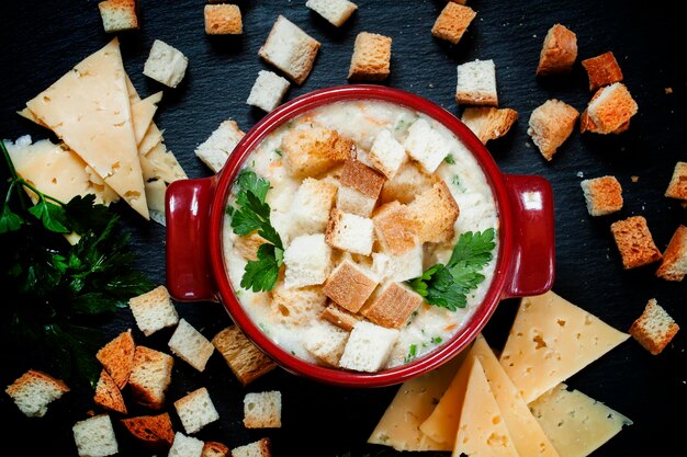 Käsesuppe mit Croutons in roter, portionierter Topf-Draufsicht