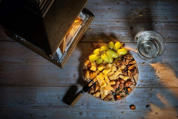 Käseteller mit verschiedenen Snacks auf dem Tisch mit zwei Gläsern Wein bei Kerzenschein.