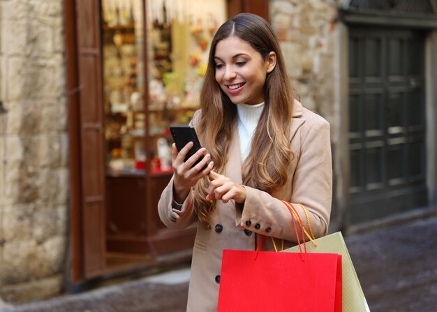 Käuferfrau, die online auf dem Smartphone in der Stadtstraße kauft.