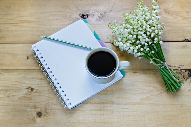 Kaffee auf einem hölzernen Hintergrund und Blumen.