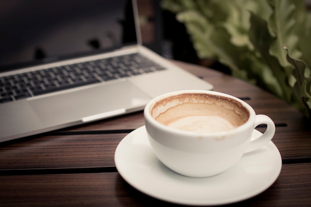Kaffee auf Tabelle mit dem Laptop, der im Café arbeitet, entspannen sich und Freizeitkonzept