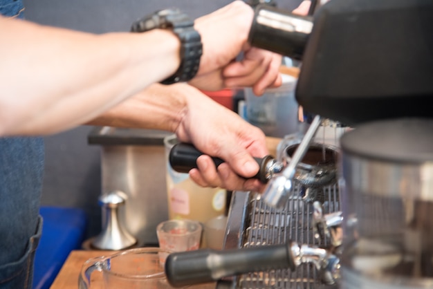 Kaffee-Barista macht Espresso aus der heißen Tasse der Kaffeemaschine