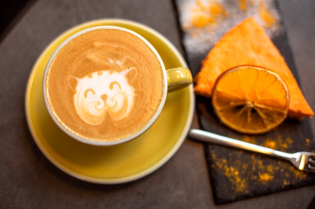 Foto kaffee-cappuccino in gelber tasse mit käsekuchen im café