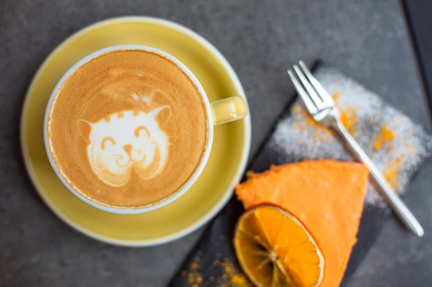 Foto kaffee-cappuccino in gelber tasse mit käsekuchen im café